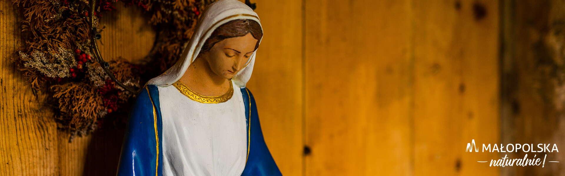 Figura Matki Bożej na drewnianym tle, w prawym dolnym rogu logo - napis Małopolska naturalnie