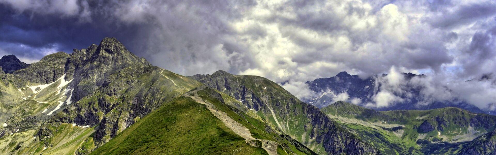 Kasprowy Wierch Tatry, zazieleniony szczyt nad którym rozciągają się chmury.