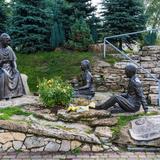 Rzeźby św. Jana Pawła II i słuchającej go pary w parku.