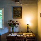 Oświetlone biurko, na nim lampa, dokumenty i kwiaty.