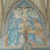 Fresk na ścianie z ukrzyżowanym Chrystusem, Matką Bożą po lewej i apostołem po prawej, na niebieskim tle pod jasnym sklepieniem.
