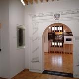 Przejście do wystawy dokumentującej dzieje Oświęcimia w czasach zaboru austriackiego w ratuszu oświęcimskim. Wokół otworu drzwiowego wymalowany łuk wsparty na dwóch kolumnach.