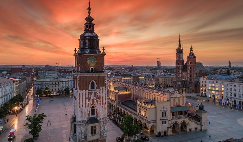 Wieża Ratuszowa, sukiennice i Kościół Mariacki na krakowskim Rynku na tle czerwonego nieba po zachodzie słońca