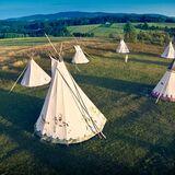 7 indiańskich namiotów ustawionych na łące w zielonym krajobrazie Pogórzy. Zdjęcie z drona.