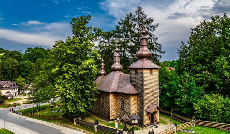 Widok na drewnianą cerkiew wśród drzew.