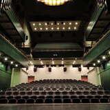 Duża sala konferencyjna ze sceną i kilkunastoma rzędami foteli w układzie teatralnym