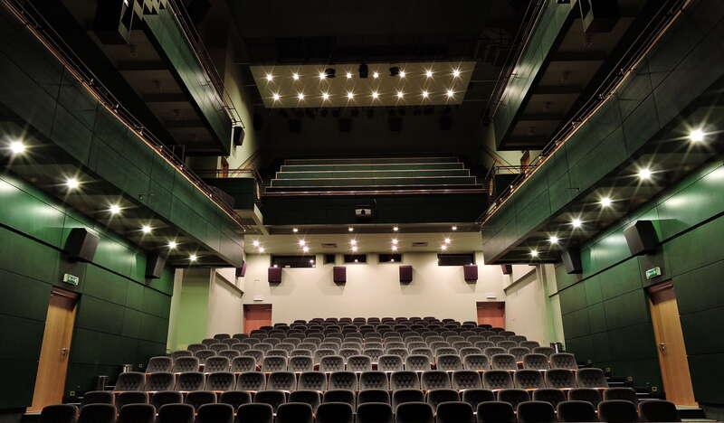 Duża sala konferencyjna ze sceną i kilkunastoma rzędami foteli w układzie teatralnym