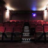 Mała sala kinowa w kilkoma rzędami foteli w układzie teatralnym