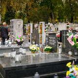 Rzędy grobów na Cmentarzu Salwatorskim w Krakowie. Na każdym z nich stoją znicze oraz kwiaty. Przy jednym z grobów stoi mężczyzna w kurtce.