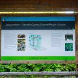 Widok na drewnianą tablice informacyjną dotycząca ośrodka ochrony gadów i płazów w Tatrzańskim Parku Narodowym.