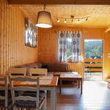 Salon połączony z jadalnią, drewniane ściany, drewniany stół i krzesła, duża kanapa.